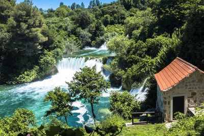 Scenic view of waterfall amidst trees and houses