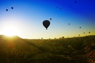 Hot air balloons on field against sky during sunset