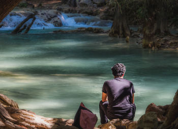 Rear view of man sitting on rock