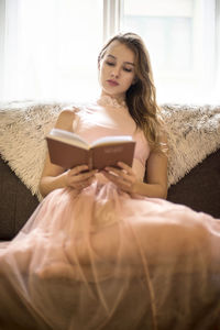 Woman looking away while sitting on sofa at home