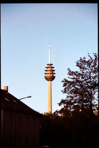 Low angle view of communications tower and buildings against sky