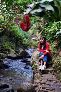 Portrait of young woman sitting on rock