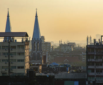 Buildings in city against sky during sunset