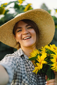 Beautiful young woman with sunflowers enjoying nature and laughing on summer sunflower field.