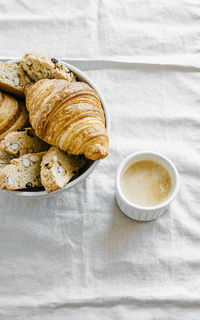 Freshly baked classic croissants and almond biscottis with cup of cappuccino on linen  background. 