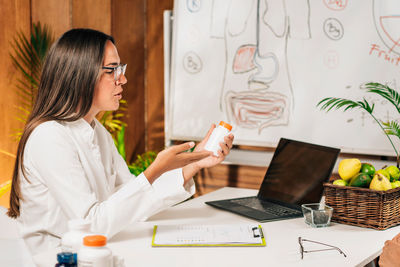 Midsection of woman using mobile phone while sitting on table