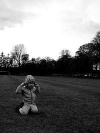 Portrait of boy sitting on field against sky