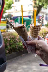 Cropped hand holding ice cream cones outdoors