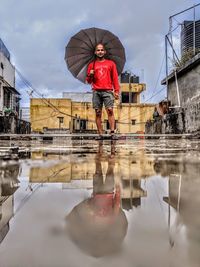 Reflection of man with umbrella in water