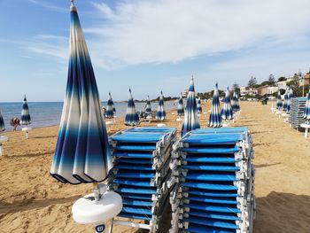 Deck chairs on beach against sky