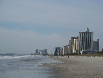 Sea and modern buildings against sky