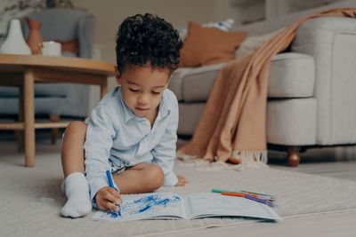 Cute boy drawing in book at home