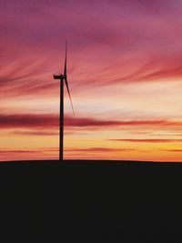 Silhouette wind turbines on landscape against romantic sky