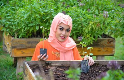 Portrait of woman holding pink flower in yard