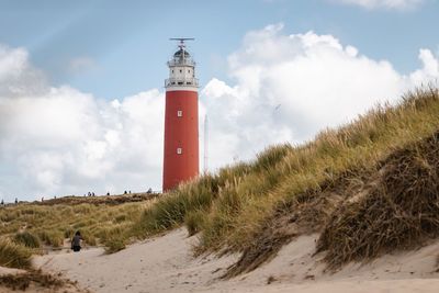 Lighthouse on beach against sky