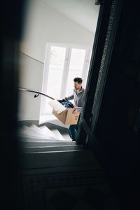 Man carrying box while moving up on steps in new house