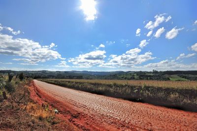 Road amidst agricultural field against sky