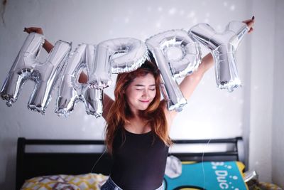 Portrait of young woman holding camera at home