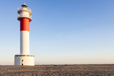 Full length of boy standing against lighthouse