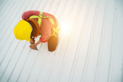 Asian construction workers are installing metal roofing sheets for industrial roof installations.