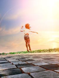Full length of woman jumping against sky during sunset