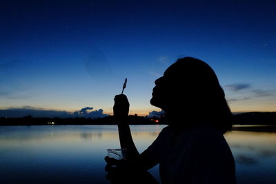 Silhouette woman blowing bubbles at sunset