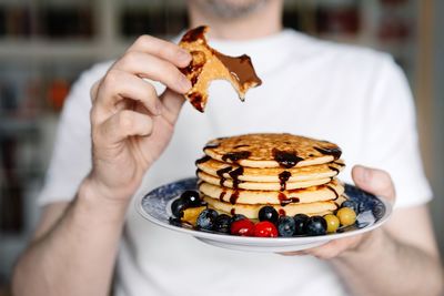 Close-up of hand holding plate with pancakes