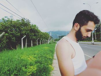 Young man looking away against trees