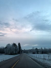 Road amidst snow covered trees against sky