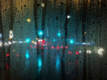 Illuminated lights seen through wet window during rainy season