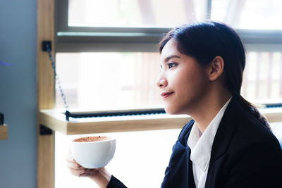 Confident businesswoman sitting with coffee mug at cafe