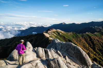 Rear view of man hiking on mountain against sky