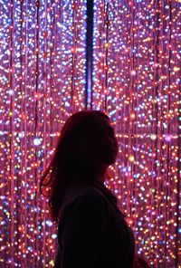 Rear view of woman standing against illuminated lights