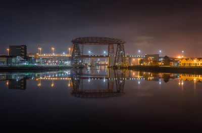 Puente transbordador over matanuska river by illuminated city against sky at night