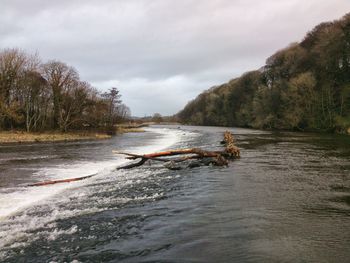 Scenic view of river against cloudy sky