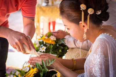 Midsection of man pouring water on bride hands