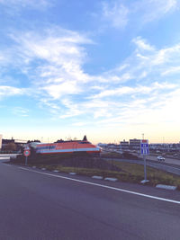 Road by buildings against sky in city