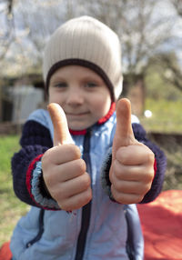 Portrait of boy gesturing thumbs up sign outdoors