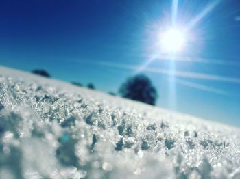 Close-up of snow against blue sky on sunny day