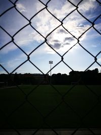 Close-up of chainlink fence against cloudy sky