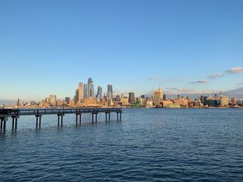 Buildings by river against sky in city