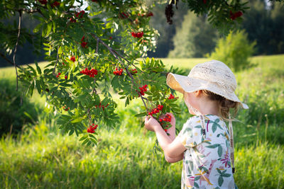 Side view of young woman standing by plants