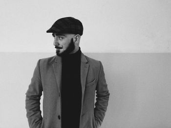 Man looking away standing against wall