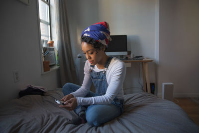 A young woman playing with a smart phone on a bed