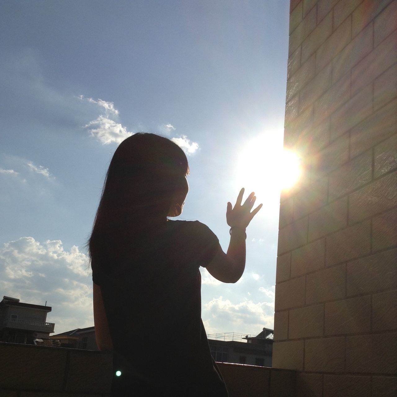 sun, sunbeam, low angle view, silhouette, sky, sunlight, lens flare, person, holding, lifestyles, human finger, back lit, statue, built structure, cloud - sky, leisure activity, human representation, sunny