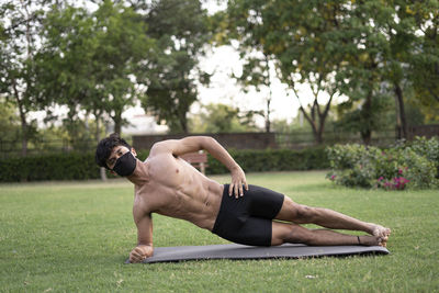 Full length of shirtless man sitting on grass