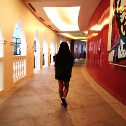 Rear view of woman in illuminated corridor