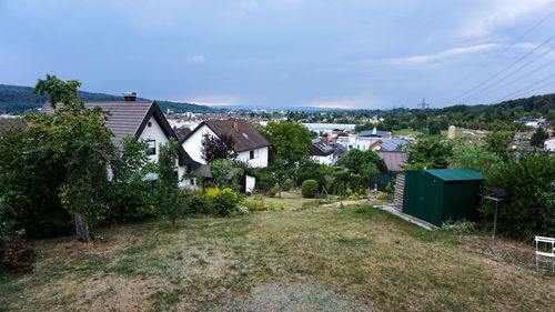 Houses amidst trees and buildings against sky