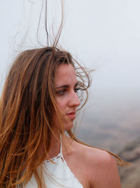 Portrait of woman with hair blowing in the wind in dark and gloomy landscape