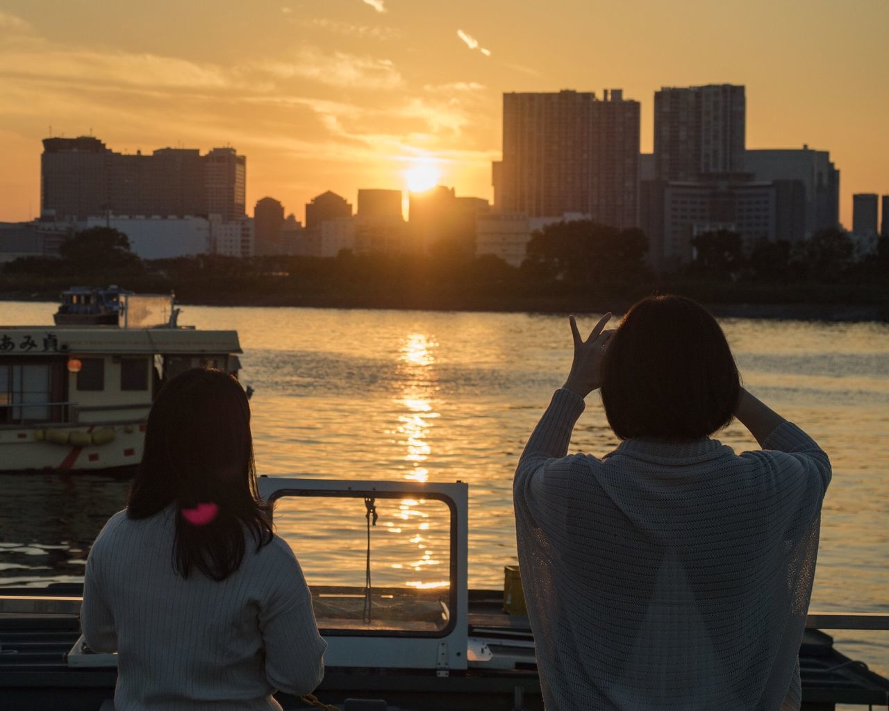 rear view, sunset, building exterior, architecture, water, men, built structure, city, leisure activity, transportation, mode of transport, person, lifestyles, orange color, river, urban skyline, city life, sky, modern, hobbies, sea, journey